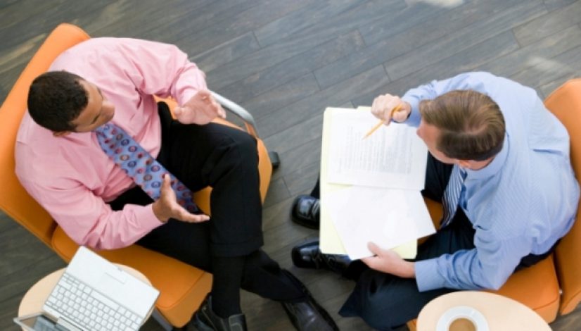 Overhead View Of Two Businessmen Having Meeting In Office Lobby